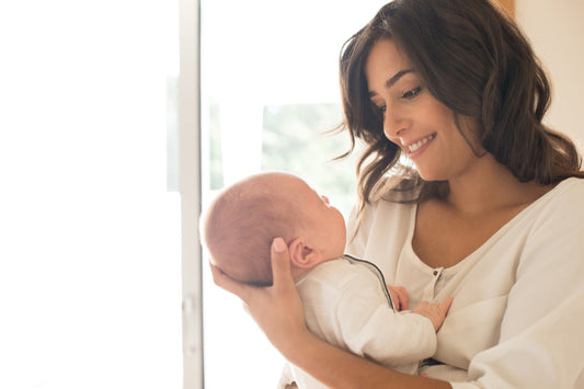 A smiling mother holding her newborn, representing the peace of mind provided by reliable DNA tests for IVF and fertility treatments.