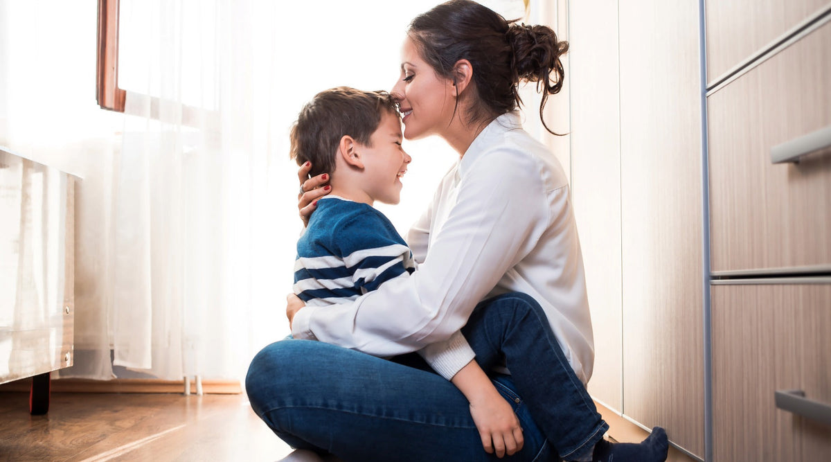 Boy mom smiling and kissing her son’s forehead, showing the lifelong DNA bond between mother and child.