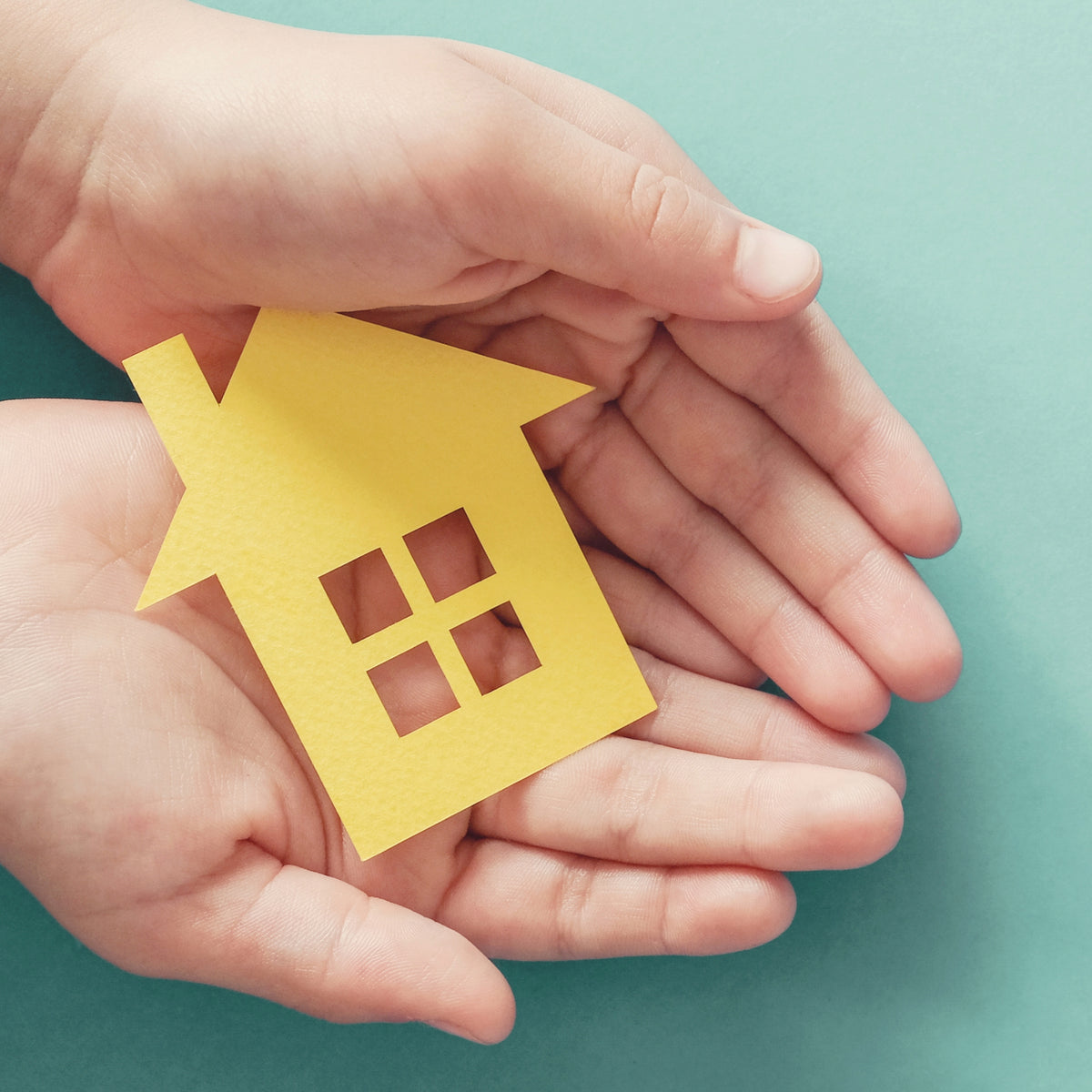 Hands holding a yellow house cutout, symbolizing safe, private, and reliable at-home DNA testing for families.