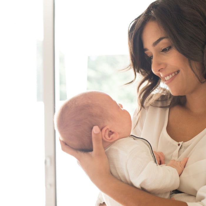 A smiling mother holding her newborn, representing the peace of mind provided by reliable DNA tests for IVF and fertility treatments.