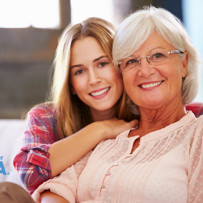 A young woman and her grandmother smiling together on a couch, with the My Forever DNA logo.