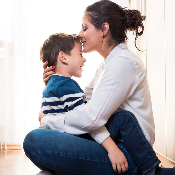 Boy mom smiling and kissing her son’s forehead, showing the lifelong DNA bond between mother and child.