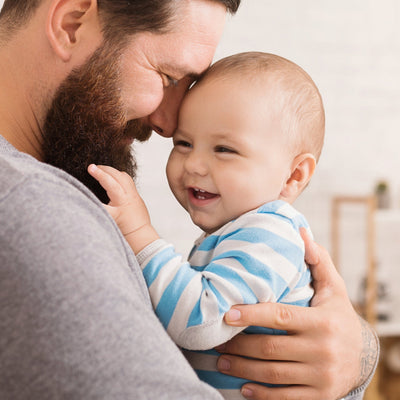 A joyful father embraces his smiling baby, their foreheads touching. The image reflects warmth, bonding, and the importance of truth in paternity testing.