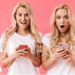 Excited twin sisters holding smartphones with shocked expressions, discovering their zygosity results with My Forever DNA's Twin Zygosity Genetic Testing in Omaha, NE.