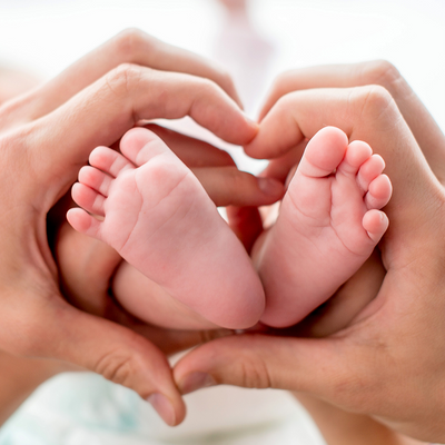Close-up of baby feet gently held in heart-shaped hands, symbolizing love, family connection, and My Forever DNA home paternity testing services.